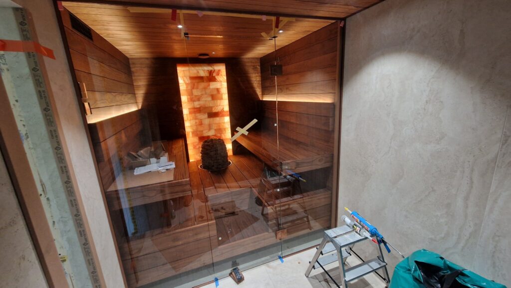 Modernne saun pruunist puidust sisustusega, mille keskel asub keris.